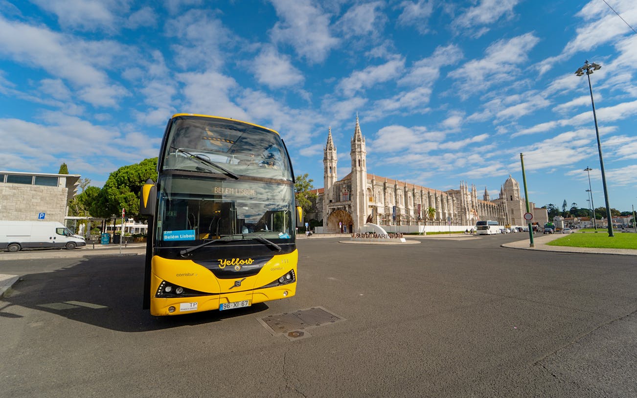 Yellow bus in front of Jerónimos Monastery during Lisbon Hop-on Hop-off tour.