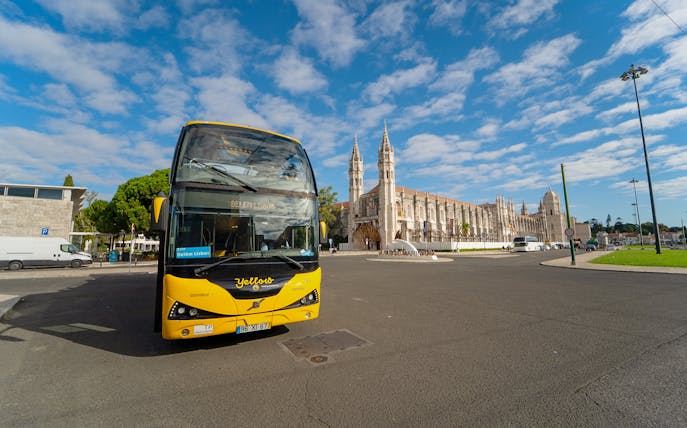 Yellow bus in front of Jerónimos Monastery during Lisbon Hop-on Hop-off tour.