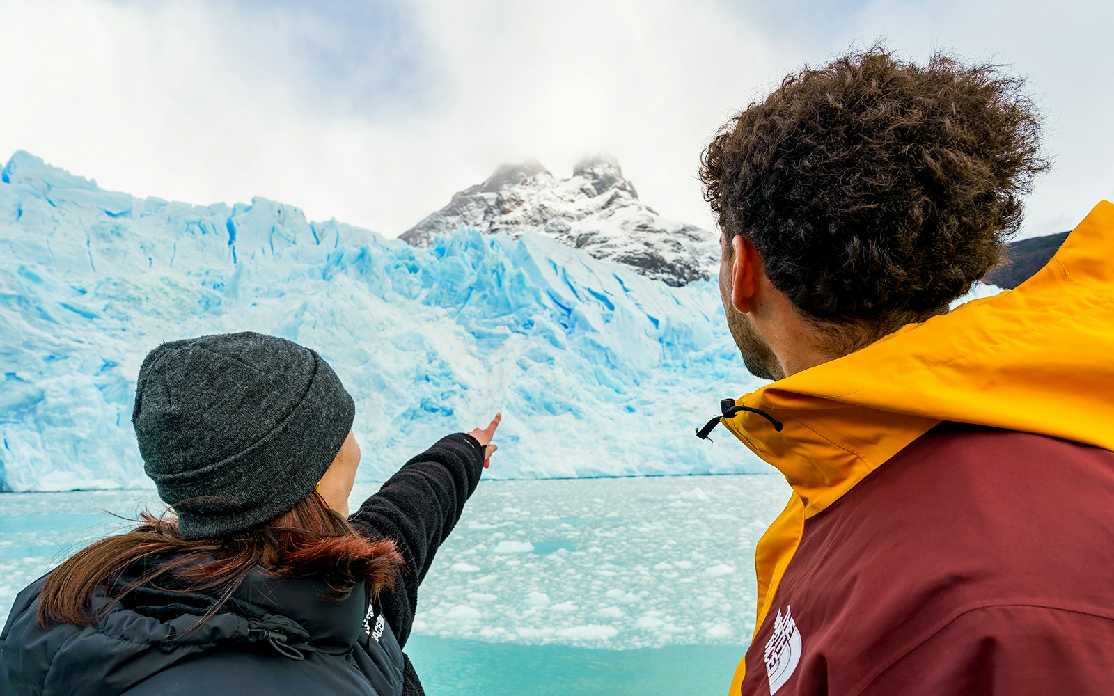Tourists on a boat pointing at Perito Moreno Glacier in Argentina.