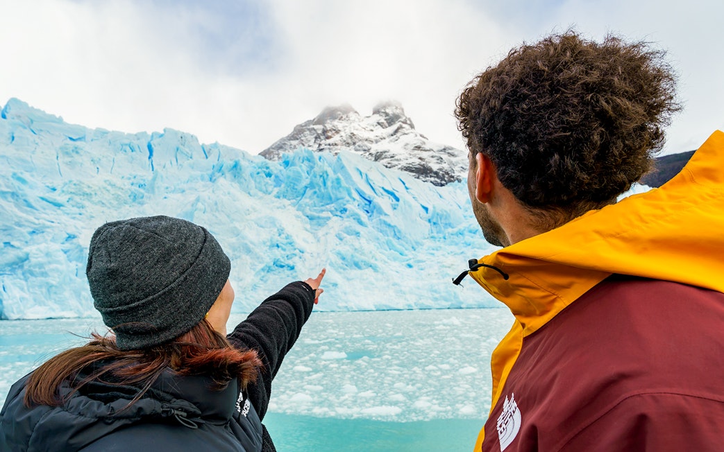 Tourists on a boat pointing at Perito Moreno Glacier in Argentina.