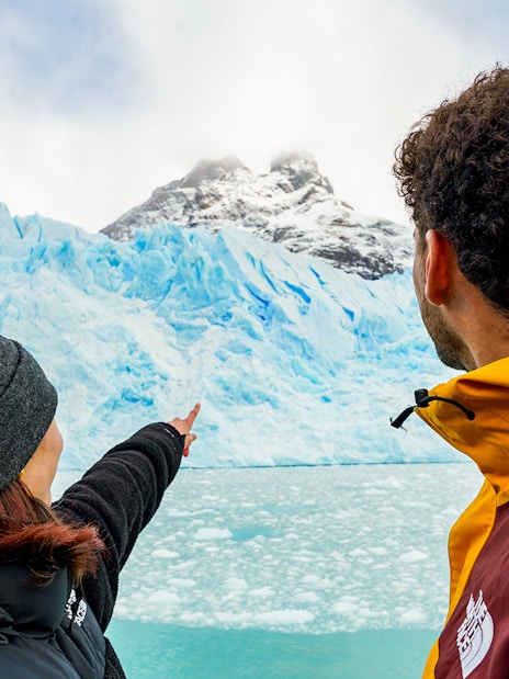 Tourists on a boat pointing at Perito Moreno Glacier in Argentina.