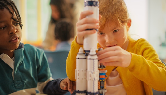 Children assembling a model spacecraft in a workshop.