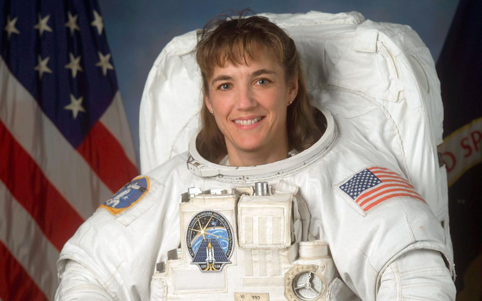 Heidi Piper in astronaut suit with helmet, space background.