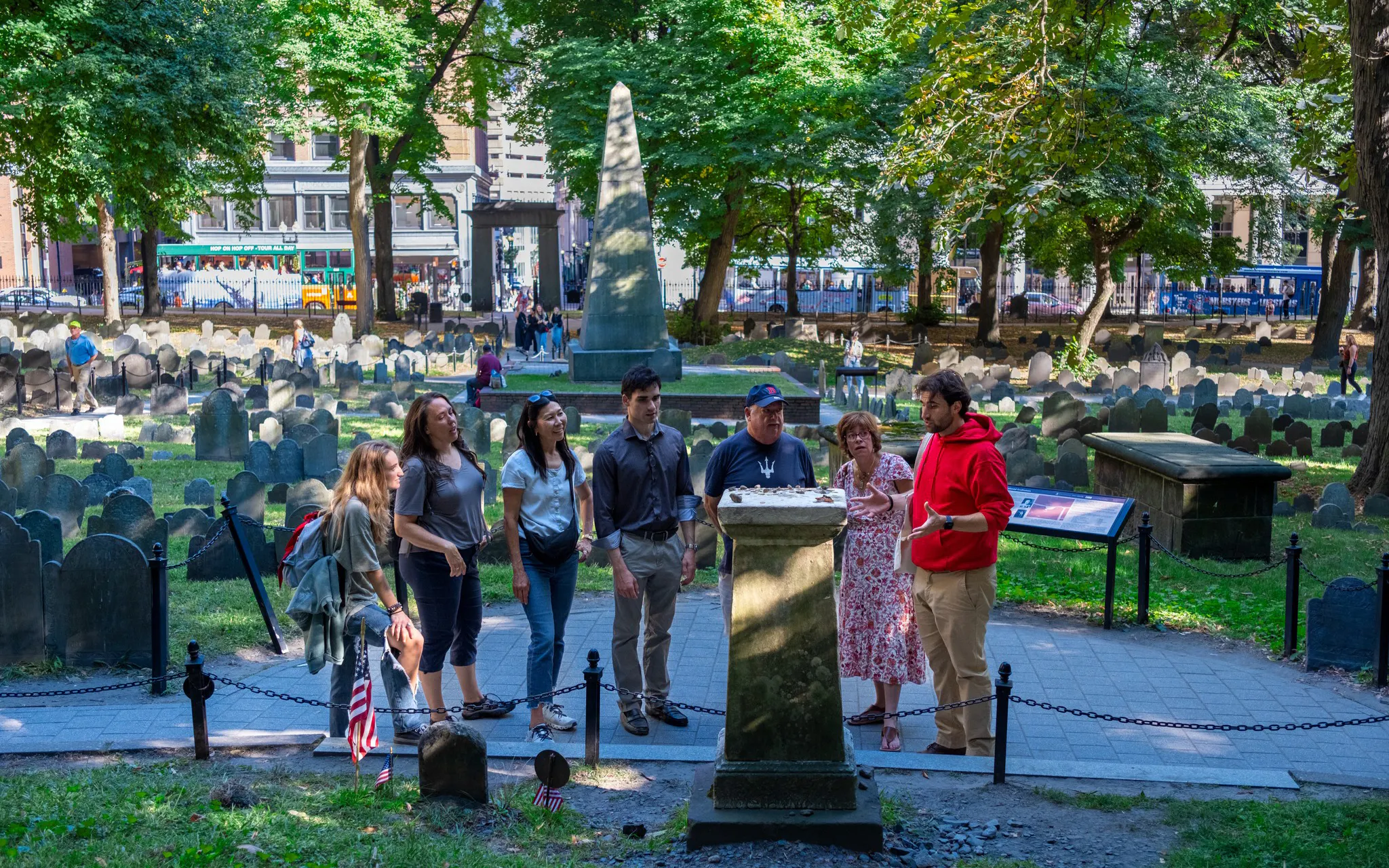 Tour group at Granary Burying Ground, Boston, Massachusetts, with historic gravestones and obelisk.