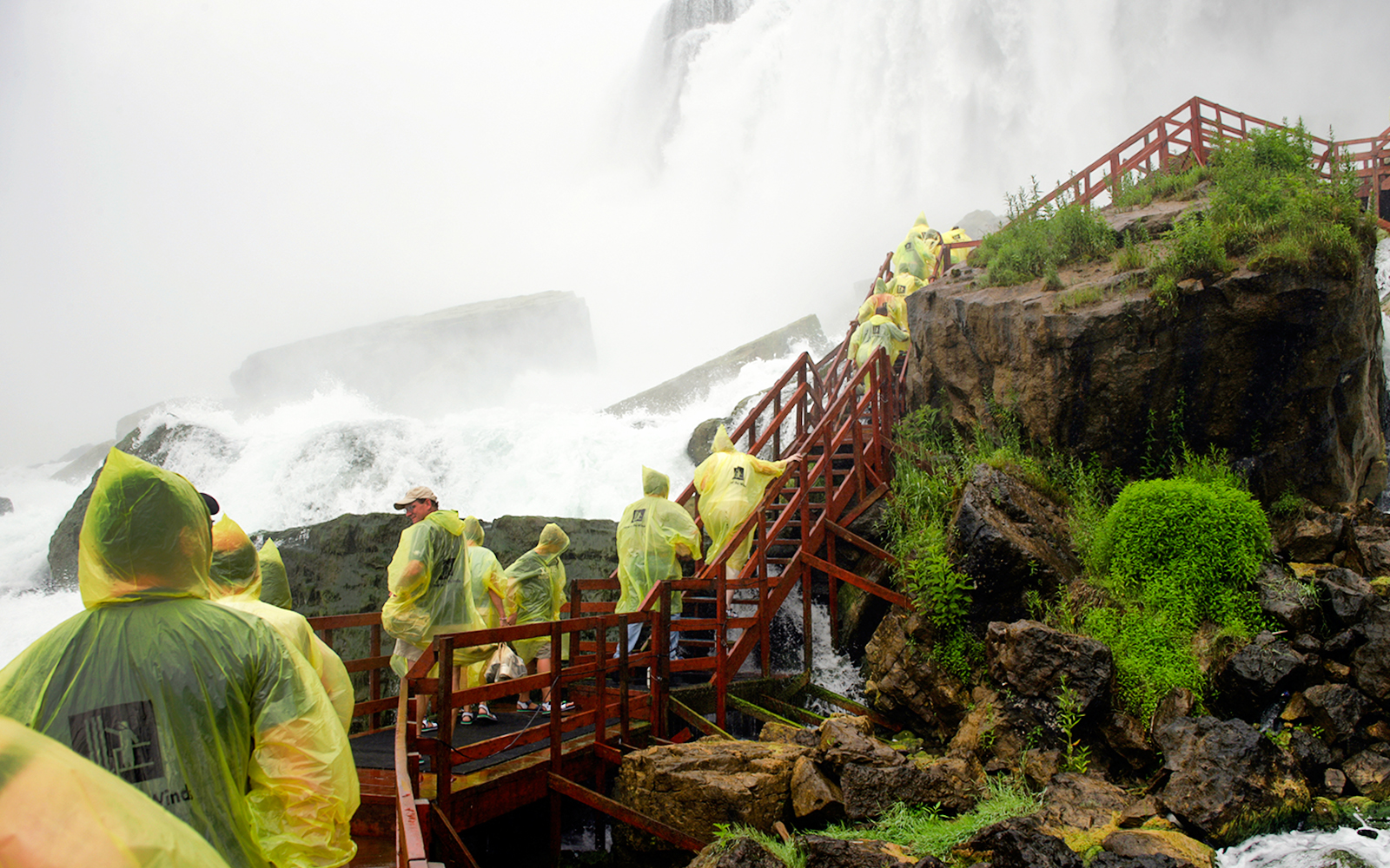 Visitors in yellow ponchos on wooden walkways at Cave of the Winds, Niagara Falls.