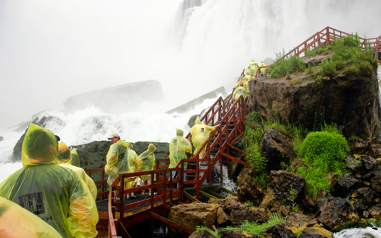 Visitors in yellow ponchos on wooden walkways at Cave of the Winds, Niagara Falls.