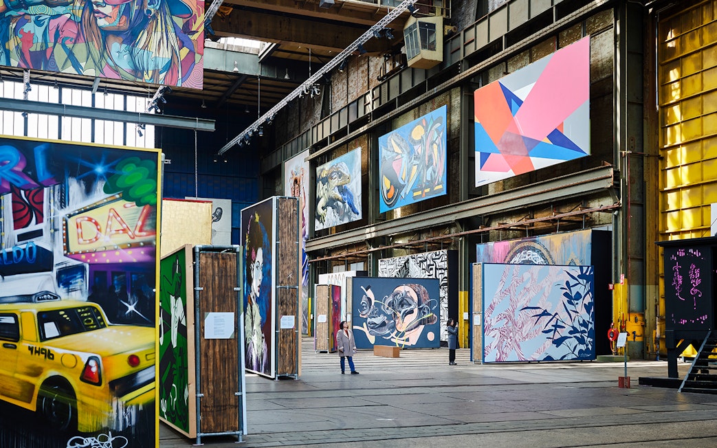 Straat Museum exhibits featuring vibrant street art and large murals in an industrial space.
