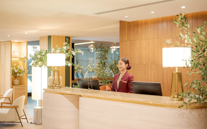 Reception desk at Coral Airport Lounges, Suvarnabhumi Airport, with staff member.
