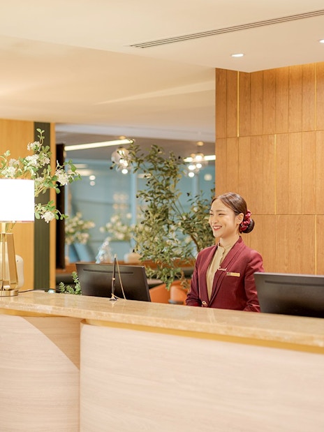 Reception desk at Coral Airport Lounges, Suvarnabhumi Airport, with staff member.