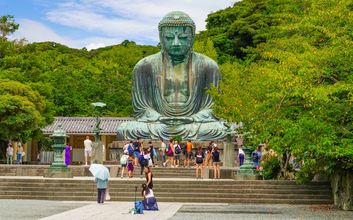 Tourists visiting the Kamakura Great Buddha statue on a day tour from Tokyo.