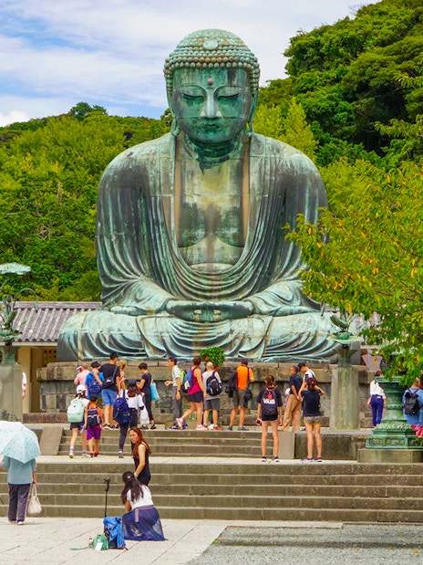Tourists visiting the Kamakura Great Buddha statue on a day tour from Tokyo.