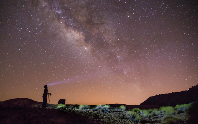 Stargazer with flashlight under Milky Way in Teide National Park, Tenerife.