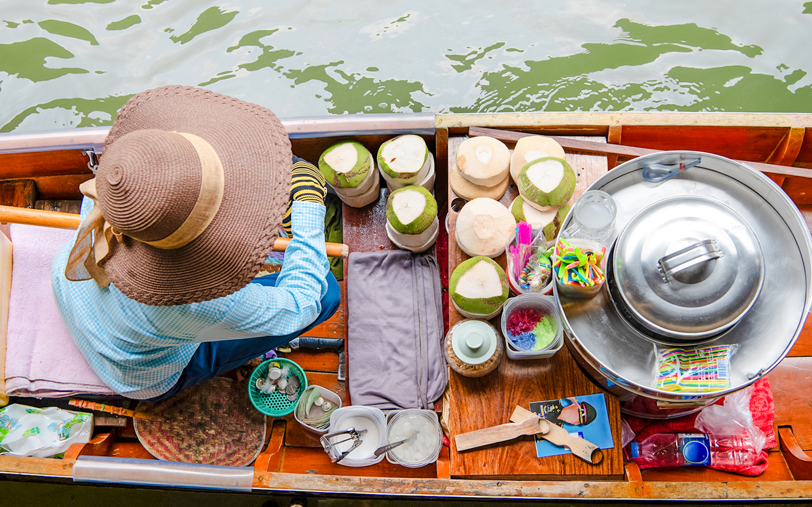 Woman selling coconut ice cream from a boat at a floating market.