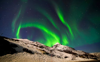 Northern Lights over snowy mountains during a 3-hour catamaran tour.