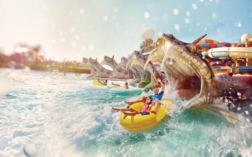 Visitors enjoying Slithers Slides at YAS Water Park, Abu Dhabi, on a yellow raft.