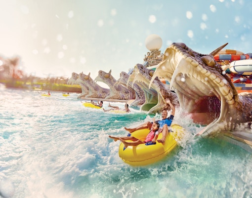 Visitors enjoying Slithers Slides at YAS Water Park, Abu Dhabi, on a yellow raft.