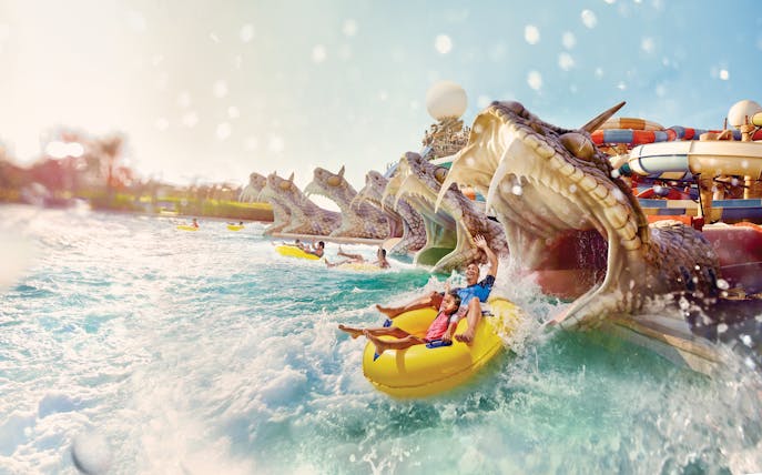 Visitors enjoying Slithers Slides at YAS Water Park, Abu Dhabi, on a yellow raft.