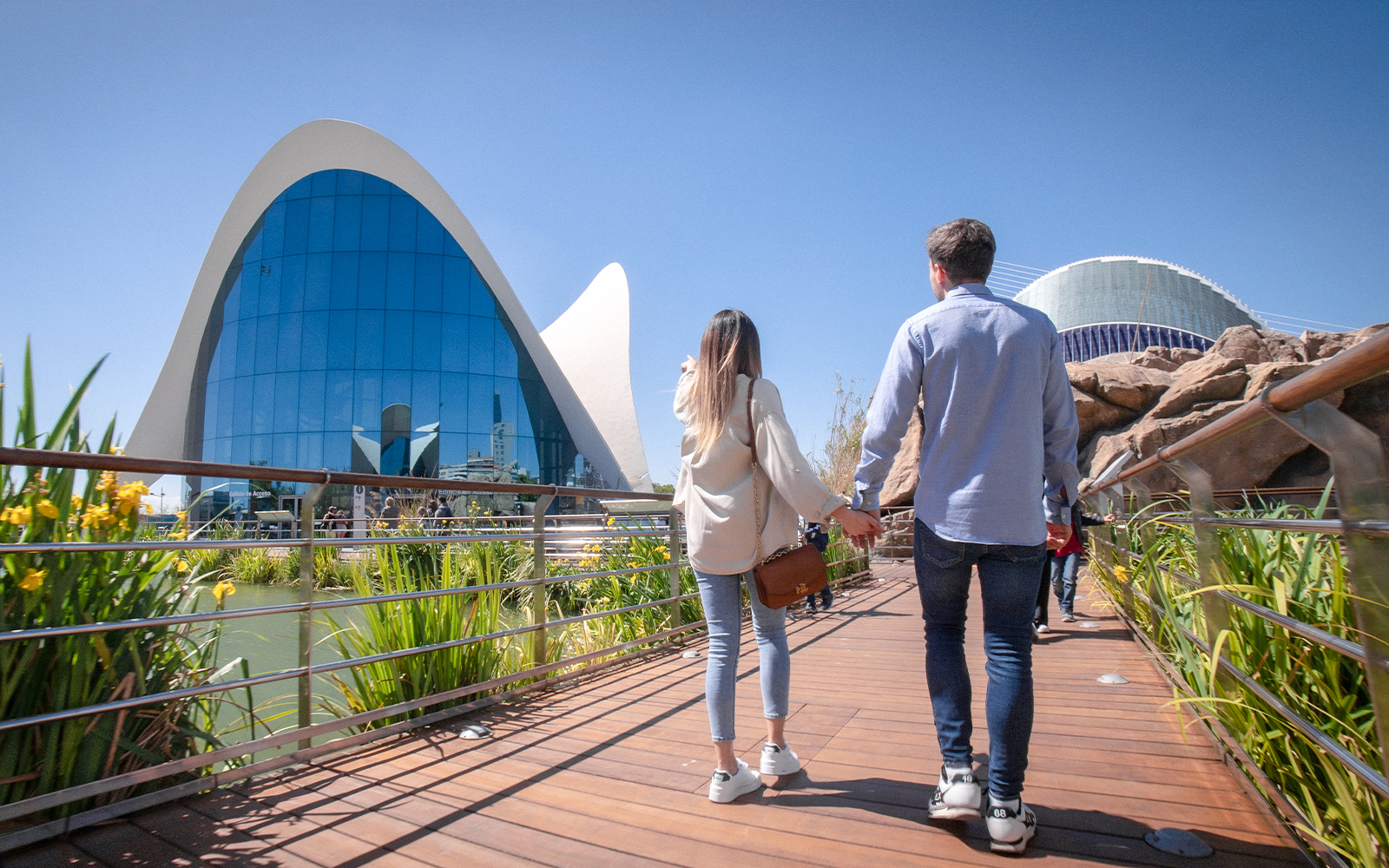 Couple walking towards Oceanogràfic Valencia, Spain, with modern architecture in view.