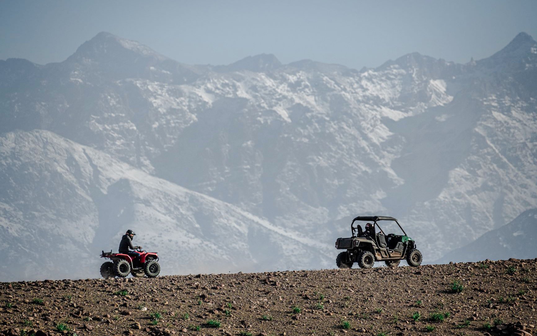 Quad biking in Agafay Desert with Atlas Mountains in the background.