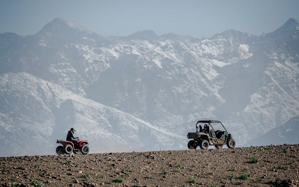 Quad biking in Agafay Desert with Atlas Mountains in the background.