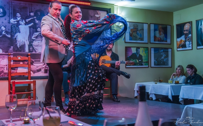 Flamenco dancers performing at Tablao La Cantaora, Seville with guitarist in background.