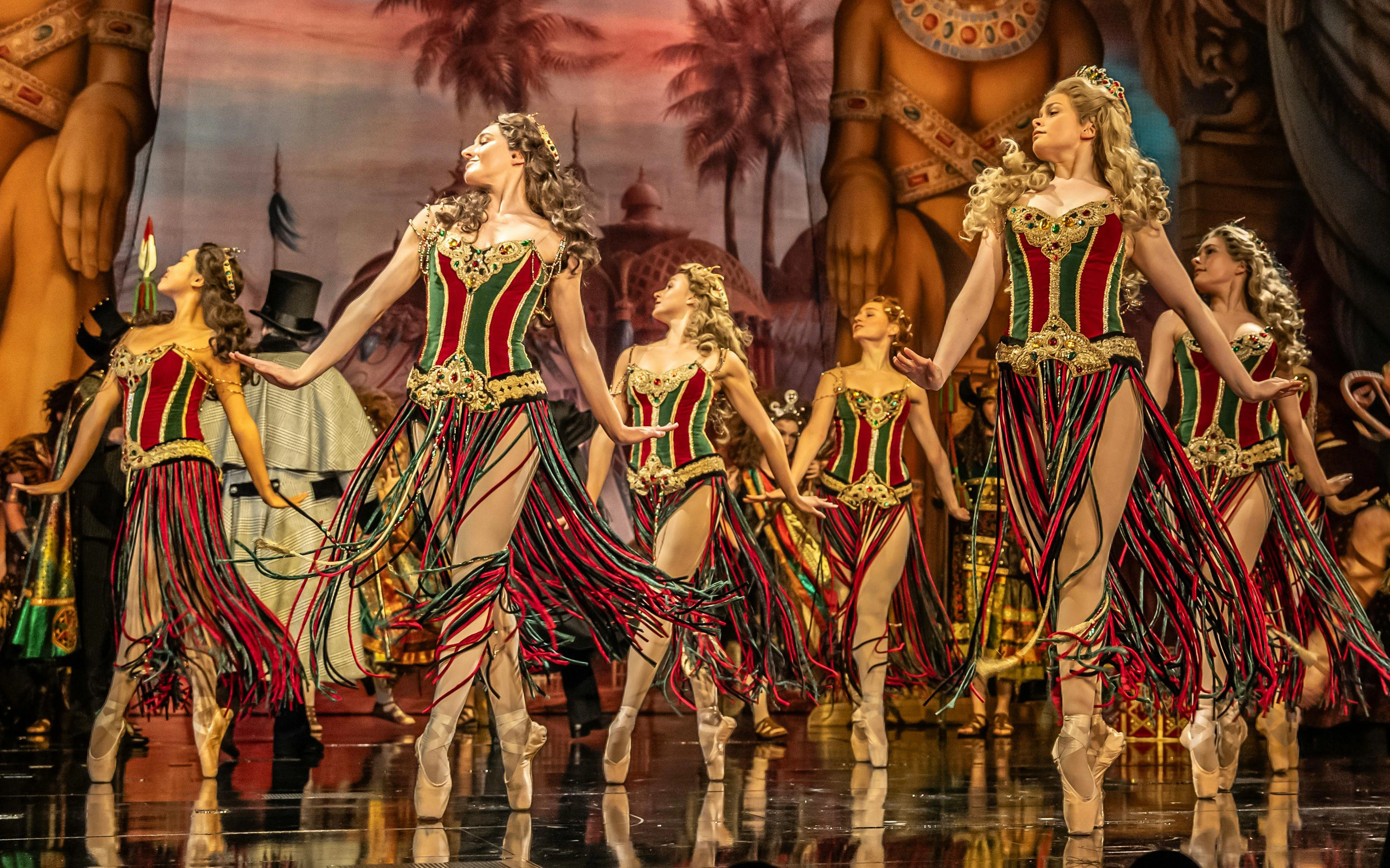 Ballet dancers in colorful costumes performing in a Phantom production scene.