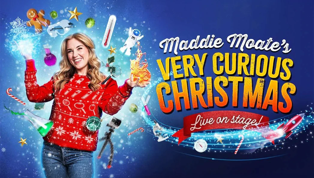 Performer in festive sweater surrounded by Christmas and science-themed items for Maddie's Curious Christmas.