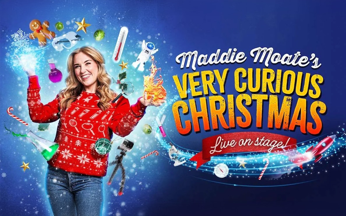 Performer in festive sweater surrounded by Christmas and science-themed items for Maddie's Curious Christmas.
