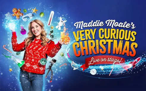 Performer in festive sweater surrounded by Christmas and science-themed items for Maddie's Curious Christmas.