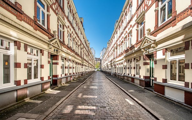 Cobblestone street in Sternschanze lined with historic buildings on a sunny day.