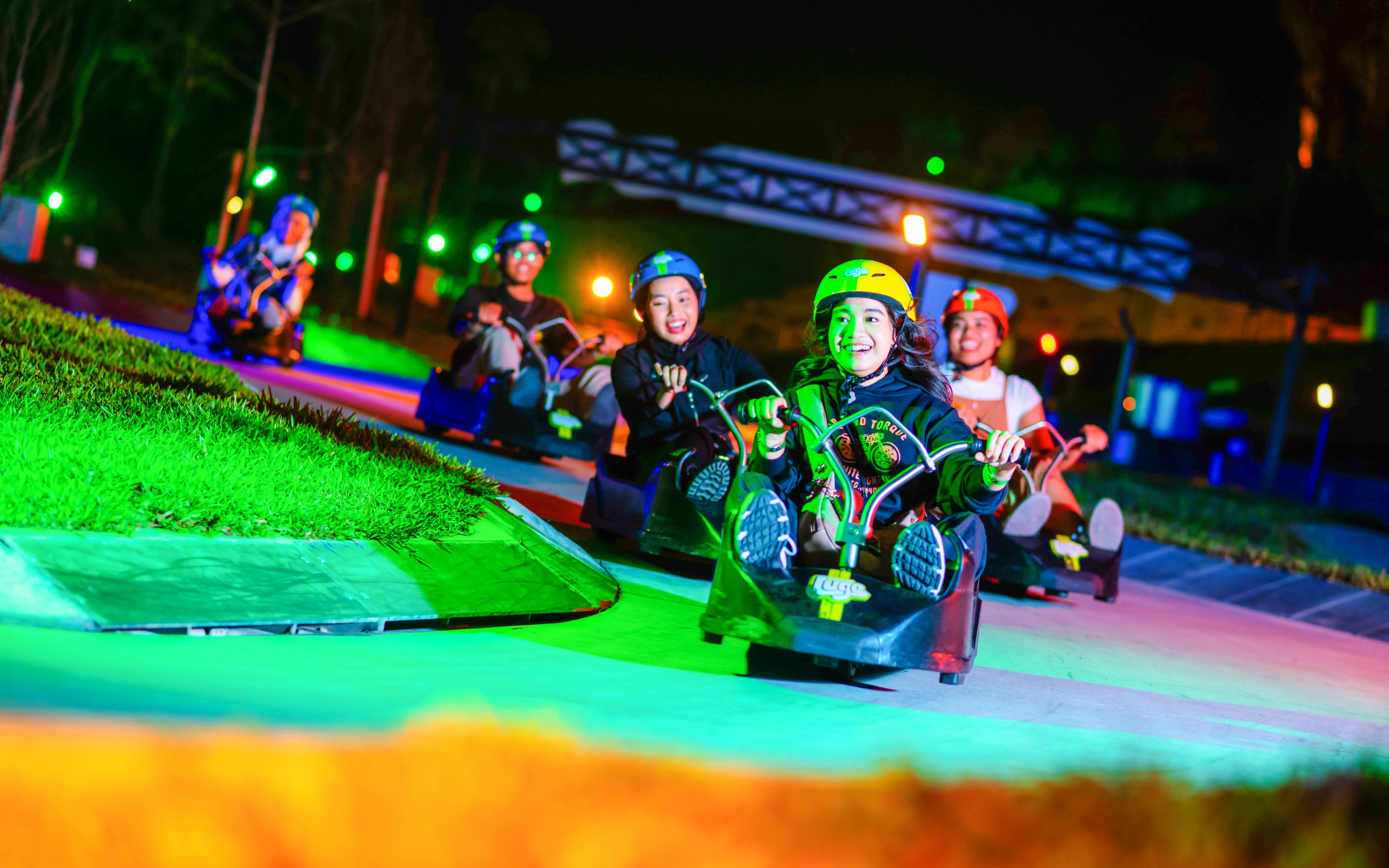 Tourists riding luge carts at night at Skyline Luge Kuala Lumpur.