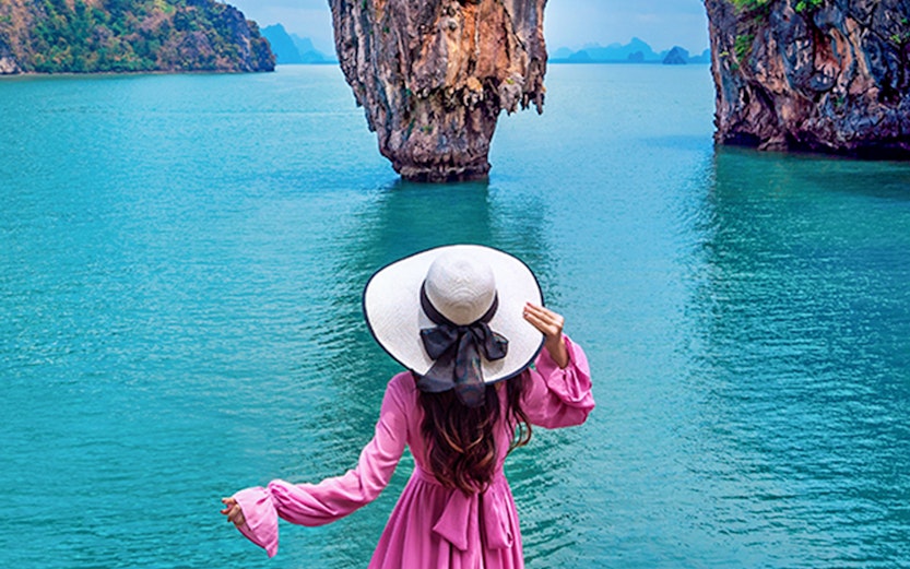 Woman in pink dress overlooking James Bond Island in Phang Nga Bay, Phuket.