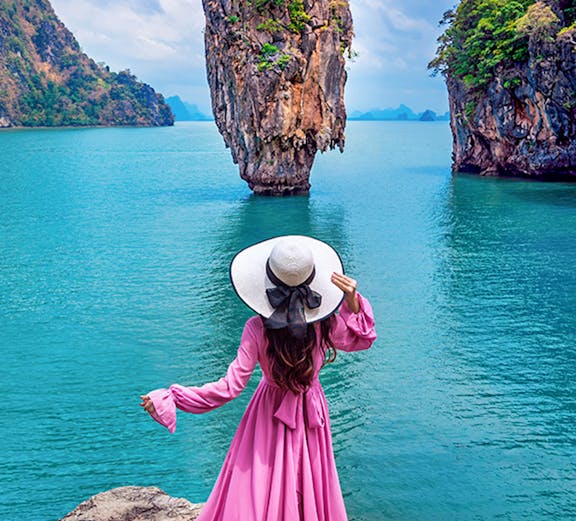 Woman in pink dress overlooking James Bond Island in Phang Nga Bay, Phuket.