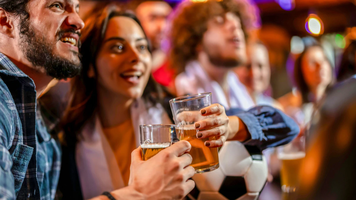 People enjoying drinks and watching a game at a bar in the Latin Quarter.
