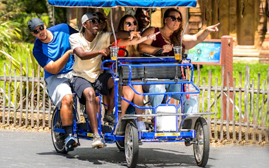 Adults enjoying a group safari cycle ride, pointing at attractions.