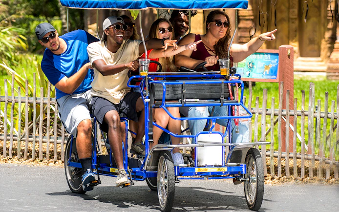 Adults enjoying a group safari cycle ride, pointing at attractions.