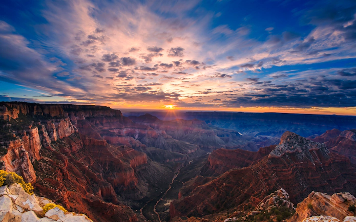 Sunset view over the Grand Canyon with dramatic clouds and layered rock formations.