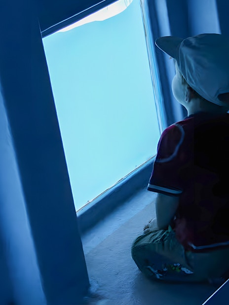 Tourist child observing marine life through glass bottom of Gran Canaria cruise boat.