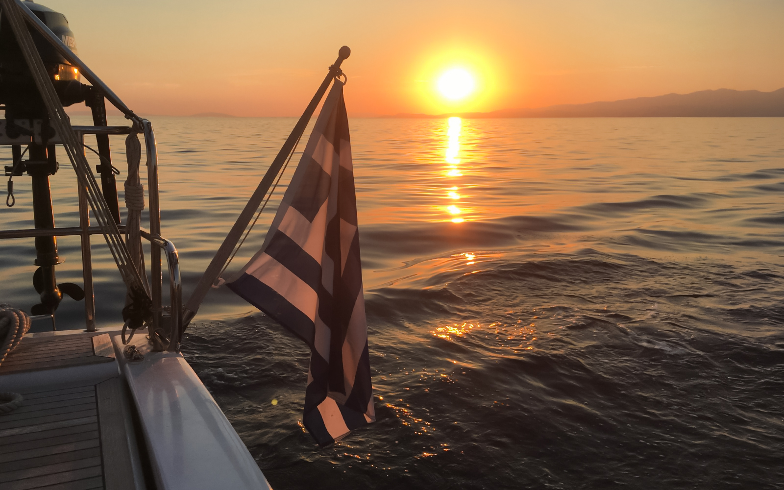 Sunset view from a cruise in Kefalonia with a Greek flag on the boat.