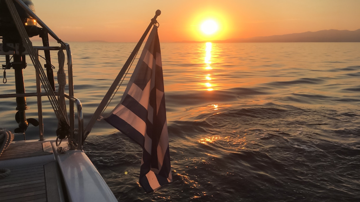 Sunset view from a cruise in Kefalonia with a Greek flag on the boat.