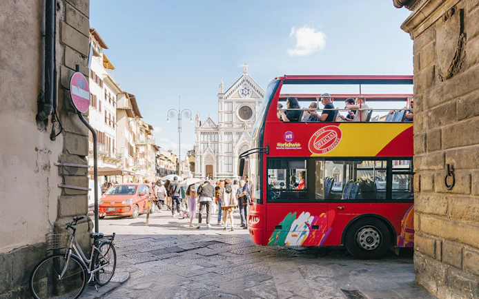 Open-top tour bus near Basilica di Santa Croce in Florence alley.