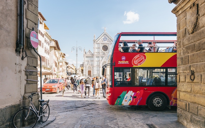 Open-top tour bus near Basilica di Santa Croce in Florence alley.
