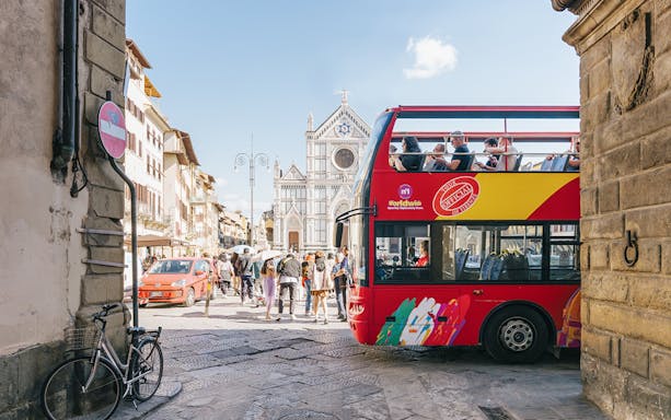 Open-top tour bus near Basilica di Santa Croce in Florence alley.