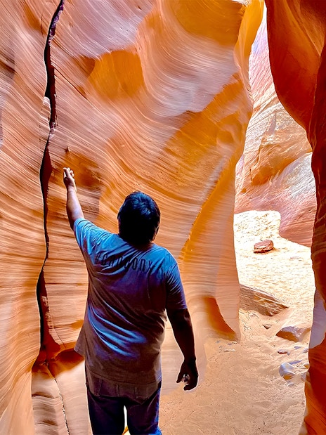 Visitor exploring narrow sandstone walls of Antelope Canyon X.