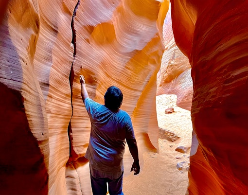 Visitor exploring narrow sandstone walls of Antelope Canyon X.