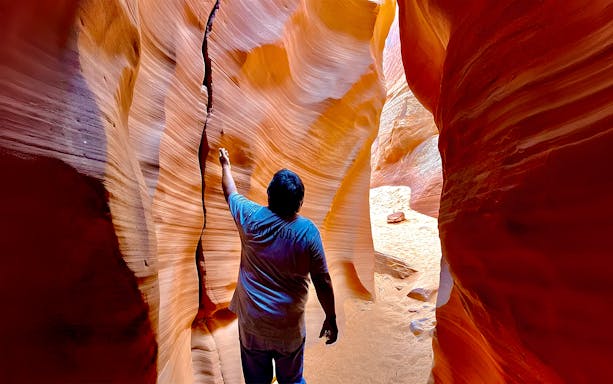 Visitor exploring narrow sandstone walls of Antelope Canyon X.