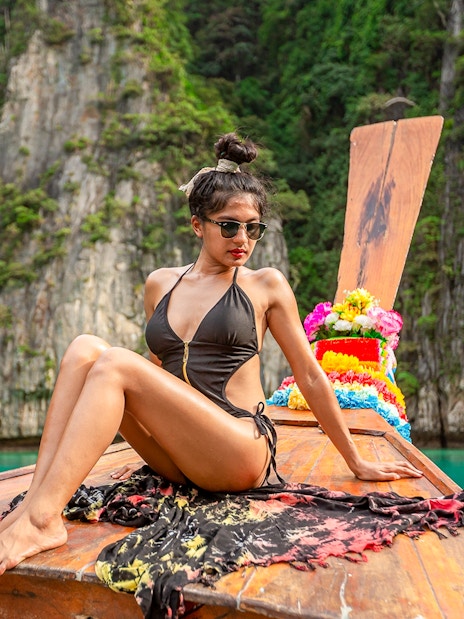 Woman relaxing on a longtail boat in a lagoon, Phi Phi Islands tour.