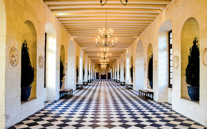Chenonceau Castle gallery with checkered floor and chandeliers.