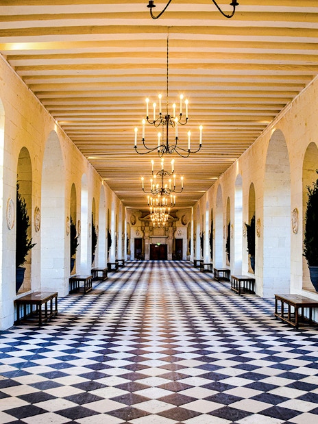 Chenonceau Castle gallery with checkered floor and chandeliers.
