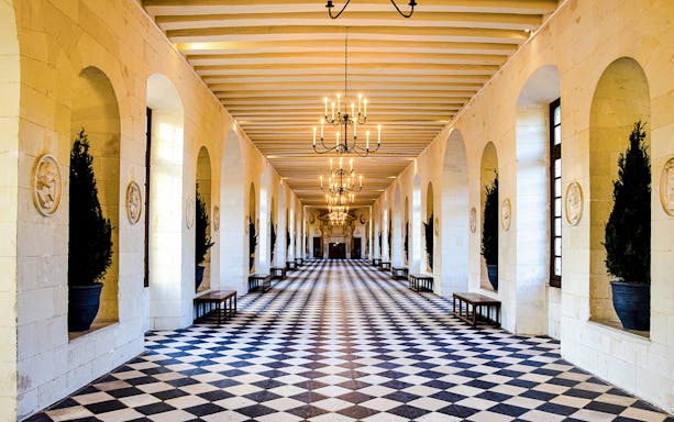 Chenonceau Castle gallery with checkered floor and chandeliers.